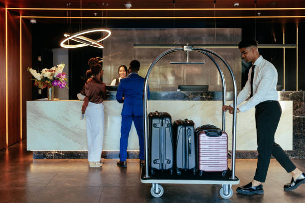 hotelbegleiter mit gepäck in der lobby. - luggage cart stock-fotos und bilder