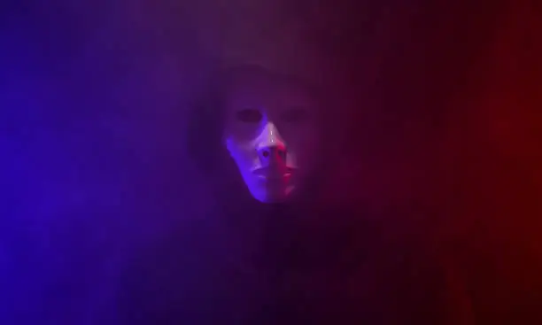 Man wearing mask with hoodie on neon background.