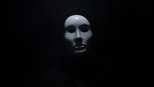 Man wearing mask with hoodie on black background.