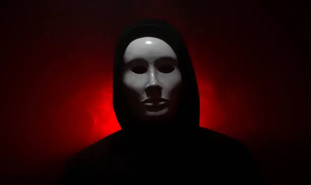 Man wearing mask with hoodie on red background.