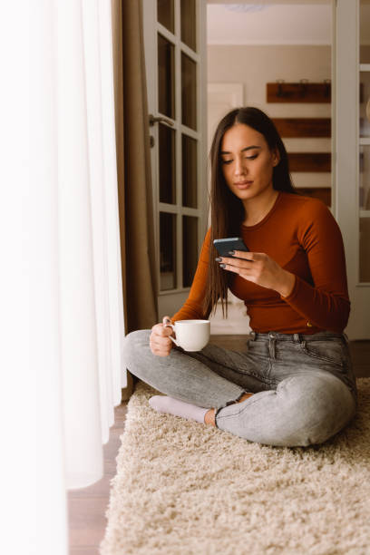 istock Woman sitting at home and using mobile phone 1428094897