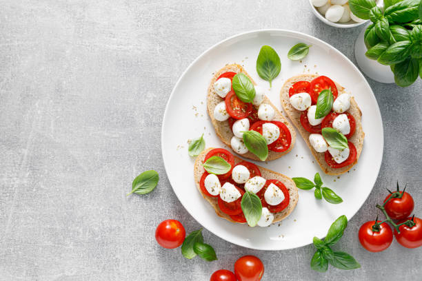 tostadas caprese con mini queso mozzarella, tomate cherry y albahaca, vista superior - mozzarella caprese salad tomato italian cuisine fotografías e imágenes de stock