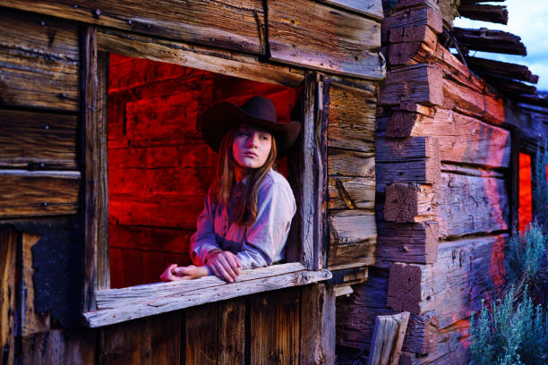 Old Cabins with Cowgirl Environmental Portrait - Dressed in western attire in and around old weathered barn cabin at dusk with glowing colorful lights.