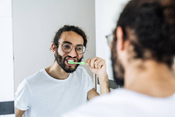 istock Multiracial man brushing teeth in bathroom in front of the mirror 1428104430