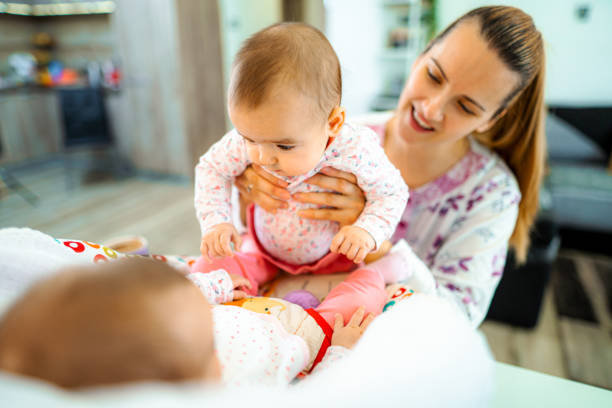 istock Young mother playing with her newborn babies at home 1428106152