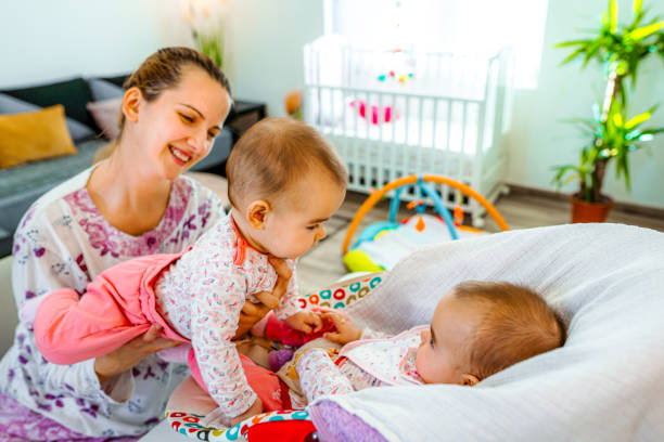 istock Young mother playing with her newborn babies at home 1428106200