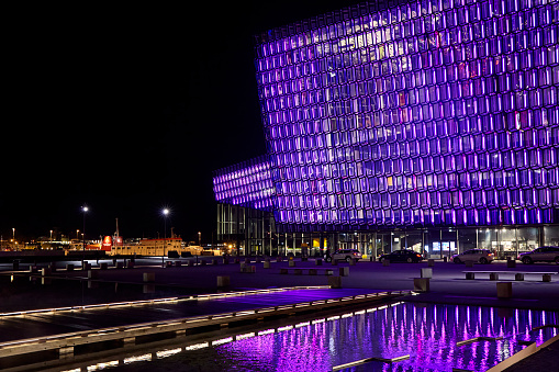 The Harpa Concert Hall illuminated glass facade at night in Reykjavik, Iceland.