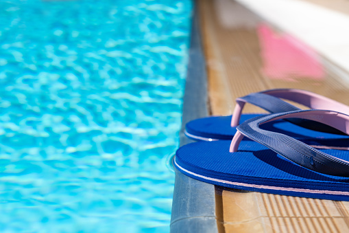 Pair of blue flip flops beside the swimming pool