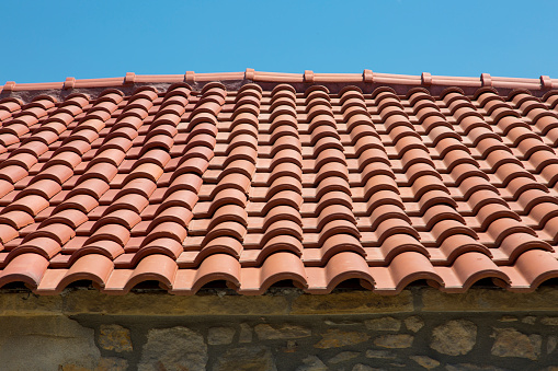 New tiled roof of house, blue sky in the background. Horizontal close-up, copy space for text message.