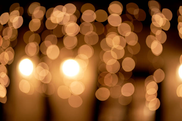 abstract glowing bokeh lights highlighted on a black background. festive golden glowing background with yellow lights. overlay bokeh for your design. - celebration imagens e fotografias de stock