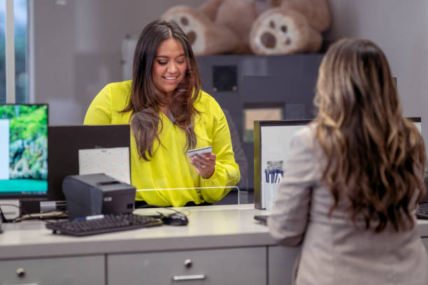 mujer entregando al cajero del banco su tarjeta de crédito - retail occupation customer advice fotografías e imágenes de stock