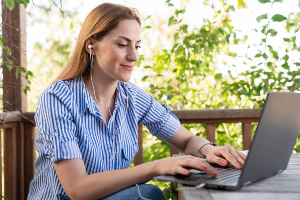 istock Young woman sitting in public park and using laptop 1428112899