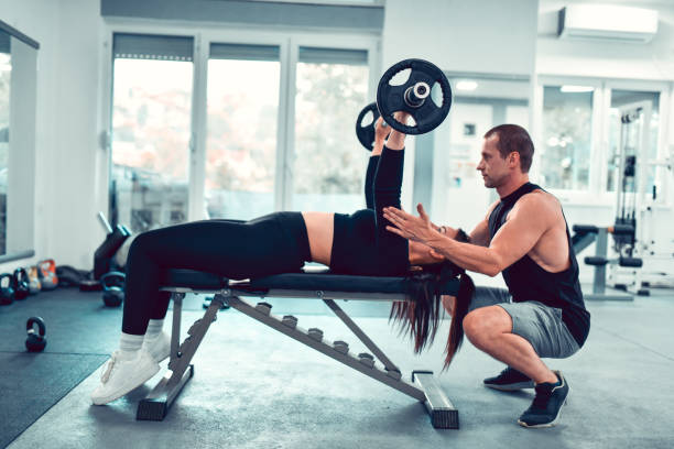 istock Athletic Female Getting Fitness Instructor Help With Bench Pressing Exercise 1428114450