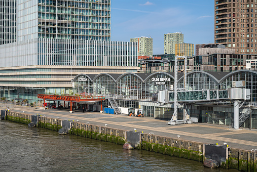 Rotterdam, Netherlands - July 11, 2022: Closeup of Cruise Terminal on Kop van Zuid dock, metal and glass construction, Parts of high rise building in back, New Meuse River in front