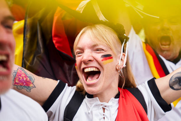 Euphoric German woman with painted face celebrating Germany national team goal Mid-shot of euphoric German football fan with painted face celebrating Germany's national team goal in crowded stadium women under 20 stock pictures, royalty-free photos & images