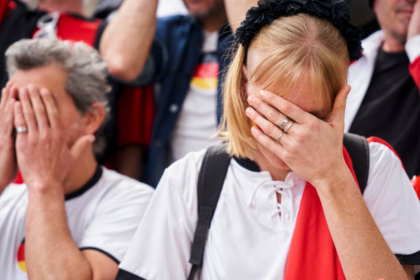 Frustrated German football fans covering their faces with hands at Germany national team match Mid-shot of frustrated German football fans covering their faces with hands at Germany national team match in crowded stadium women under 20 stock pictures, royalty-free photos & images