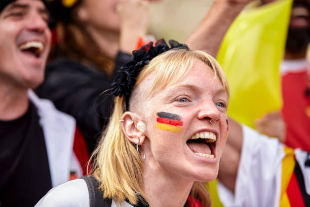 Excited German football fan chanting in crowded stadium at Germany national team match Mid-shot of excited female German football fan with painted face chanting in crowded stadium at Germany national team match women under 20 stock pictures, royalty-free photos & images