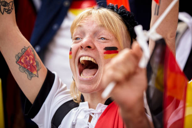 Happy German football fan celebrating after national team scores goal Mid-shot of happy German football fan with face paint celebrating in crowded stadium after national team scores goal women under 20 stock pictures, royalty-free photos & images
