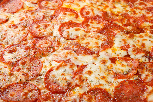 Pizza background - macro shot of italian Pepperoni pizza. It can be used as an abstract food background.