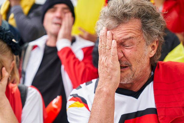 Frustrated mature German man covering his face with hand during Germany national team match Mid-shot frustrated mature German man covering his face with hand during Germany national team match in crowded stadium women under 20 stock pictures, royalty-free photos & images