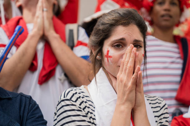 Sad English woman covering her mouth with hands after national team fails to score a goal Mid-shot of sad young English woman with white and red face paint covering her mouth with hands in frustration after national team fails to score a goal in crowded stadium women under 20 stock pictures, royalty-free photos & images