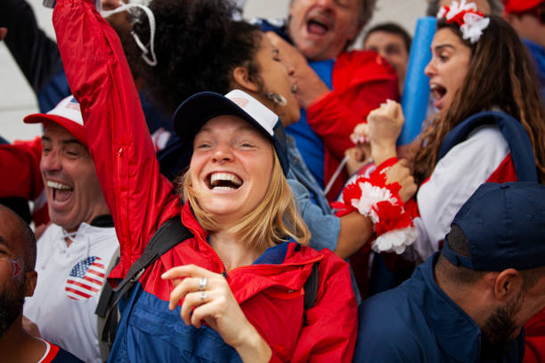 Young American woman cheering at stadium during USA national team soccer game stock photo