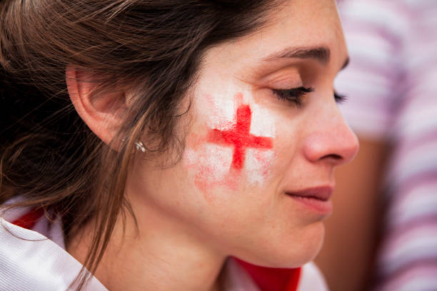 Sad English woman with white and red face paint frustrated after England national team fails to win game Close-up side shot of sad English woman with white and red face paint about to cry after England national team fails to win game in crowded stadium women under 20 stock pictures, royalty-free photos & images