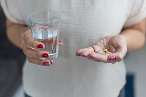 Woman taking medical pill with water