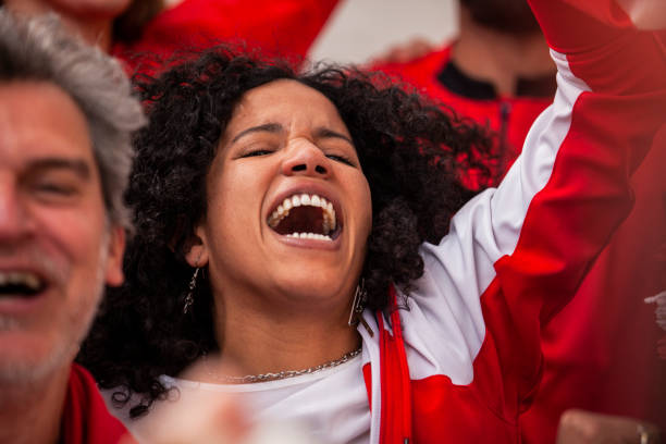 eufórico aficionado al fútbol cantando y vitoreando con el brazo levantado en gradas abarrotadas durante el partido de la selección nacional - cántico fotografías e imágenes de stock