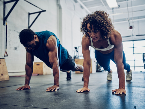 An athletic couple cross training in a gym.