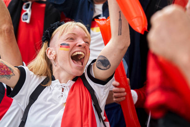 Happy German football fan with arms raised celebrating after national team scores goal Medium shot of happy German football fan with arms raised celebrating in crowded stadium after national team scores goal women under 20 stock pictures, royalty-free photos & images