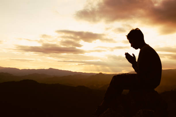 sylwetka człowieka to modlitwa do boga na górze. modląc się rękami, okazuj szacunek. - praying men god kneeling zdjęcia i obrazy z banku zdjęć