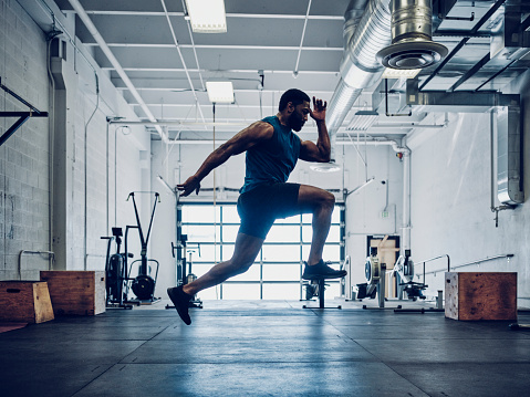 An athletic man cross training in a gym.