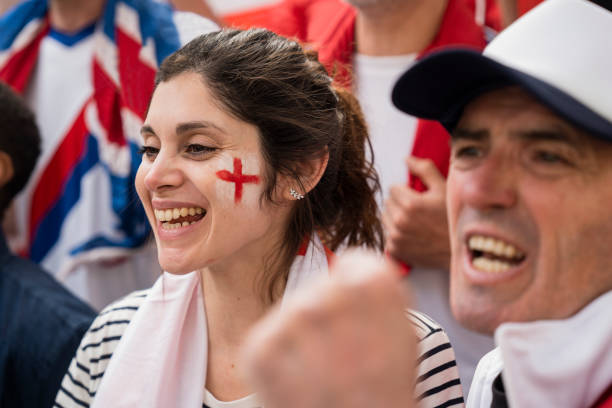 Two English football fans cheering at national team match Mid-shot of two English football fans cheering and chanting at national football team game in crowded stadium women under 20 stock pictures, royalty-free photos & images