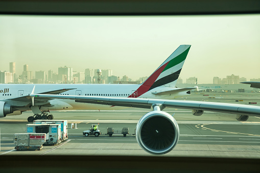 Dubai, UAE, march 2022: Airplane with EMIRATES logo in window terminal International Airport, at urban background. Concept Air Transportation industry. Copy text space