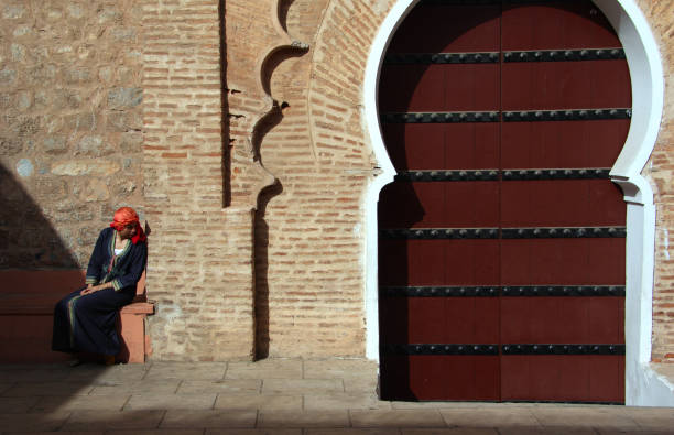 две женщины беседуют перед исторической дверью, рабат, марокко - women indigenous culture middle east traditional culture стоковые фото и изображения