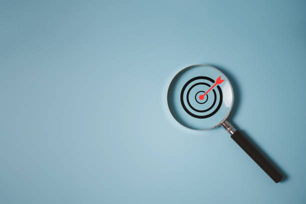 istock Target board inside of magnifier glass for focus business objective achievement concept on blue background and copy space. Search, goal, strategy, success. 1428133834