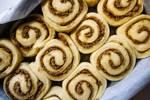 Cinnamon rolls all prepared and on their second rise before backing, all rolled up with brown sugar and spices. Naturally leavened dough adds extra depth of flavor.
