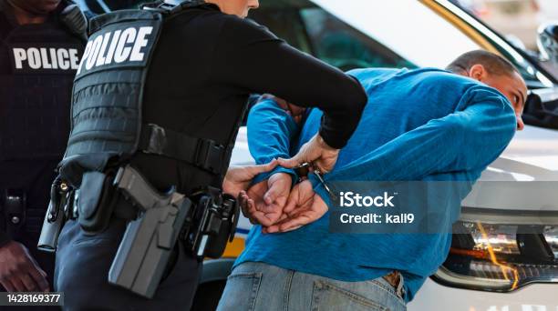Policewoman And Partner Arresting Man Stock Photo - Download Image Now - Arrest, Police Force, Crime