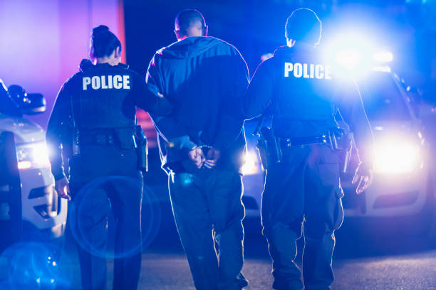 Handcuffed suspect being arrested by police at night