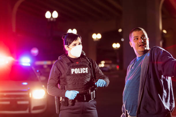 istock Policewoman in mask working at night questioning man 1428173260