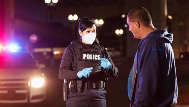 istock Policewoman in mask working at night questioning man 1428173264