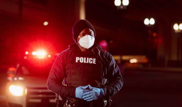 afroamerikanischer polizist nachts mit gesichtsmaske - hands clasped flash stock-fotos und bilder