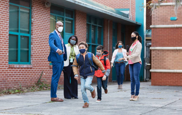 istock Teachers watch elementary students leaving school, masks 1428176074