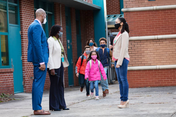 istock Teachers watch elementary students leaving school, masks 1428176614