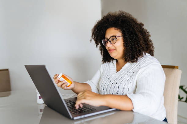 istock Woman holding medicine while using laptop 1428189646