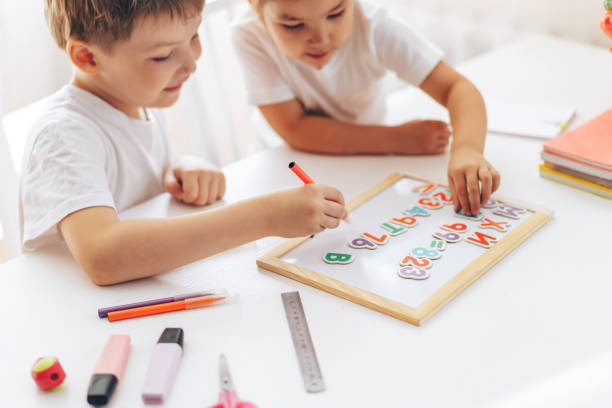 Children lay out letters and numbers on the board while sitting at the table Children lay out letters and numbers on the board while sitting at the table. report card stock pictures, royalty-free photos & images