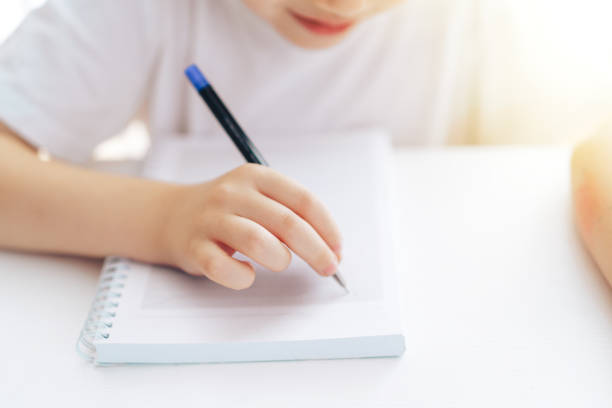 istock Child writes with a pen in a notebook with rings 1428193101
