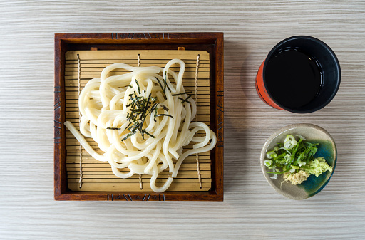 Chilled Zaru Udon, noodles with cut roasted seaweed served in a bamboo basket with a refreshing mentsuyu dipping sauce, wasabi, ginger and Bunching Onion. Top View