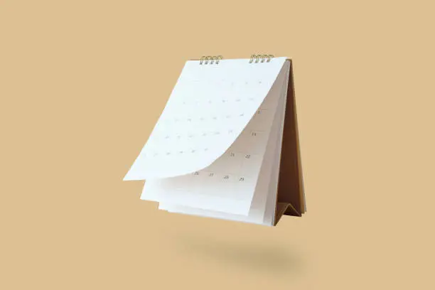 Photo of White paper desk calendar flipping page mockup isolated on brown background